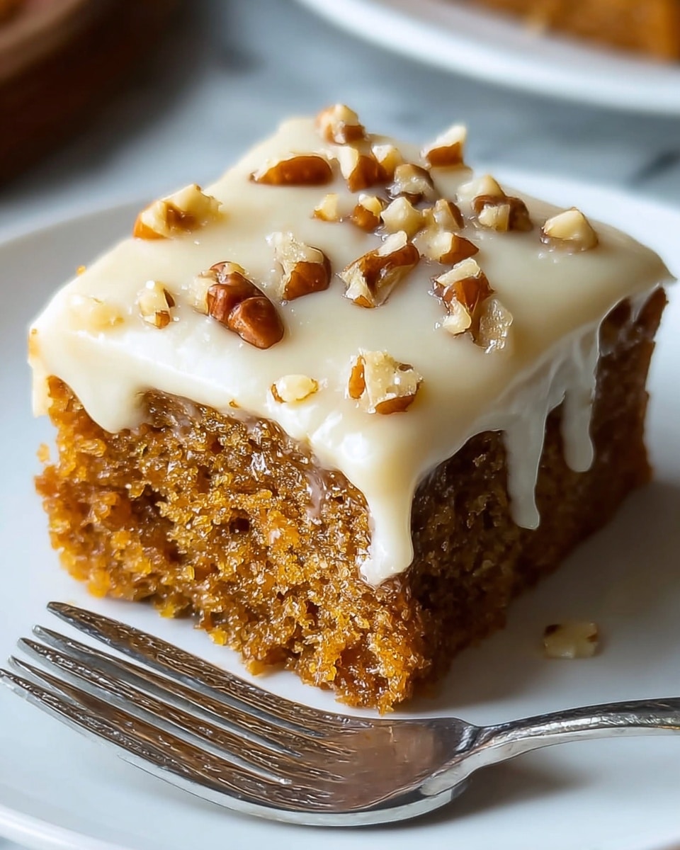 A single square piece of moist brown cake sits on a white plate with a silver fork beside it. The cake has one visible layer, covered with a smooth/off-white creamy frosting that slightly drips over the edges. On top of the frosting, there are small pieces of chopped pecans that add a crunchy texture and a darker brown color contrast. The white plate rests on a white marbled surface. photo taken with an iphone --ar 4:5 --v 7