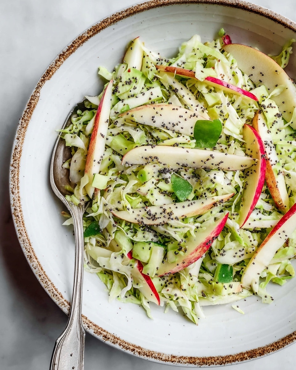A close-up view of a fresh salad in a white bowl with a speckled brown rim, filled with thin, long slices of pale green apple with red edges, shredded light and dark green cabbage, small green leaves, and thin slices of cucumber. The salad is sprinkled with small black poppy seeds, adding contrast to the mix of green and white colors. A vintage silver fork rests inside the bowl, partially covered by the salad ingredients. The bowl is placed on a white marbled surface. photo taken with an iphone --ar 4:5 --v 7