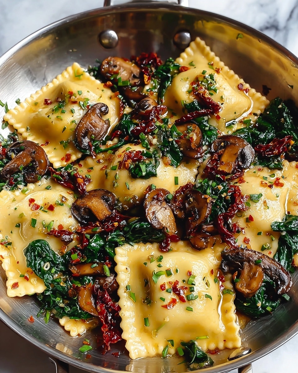 The dish shows a pan full of ravioli pasta with about three layers visually: the bottom layer is soft yellow ravioli with crimped edges, the middle layer has sautéed dark brown mushroom slices with a glossy texture, and bright green wilted spinach leaves scattered throughout, topped with thin, deep red sun-dried tomato strips and finely chopped green herbs, all lightly coated in a shiny, oily sauce mixed with small bits of roasted garlic. The pan is metallic and the whole image is set on a white marbled surface. Photo taken with an iphone --ar 4:5 --v 7