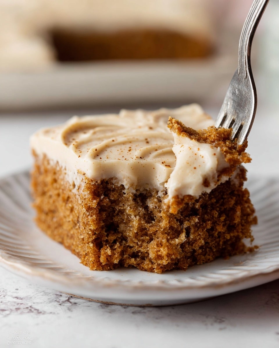 The image shows a close-up of a sliced square cake with two clear layers: the bottom layer is a moist, textured brown cake with visible crumbs, and the top layer is a thick, smooth off-white frosting lightly dusted with a fine brown powder. The cake is cut into squares and placed on a white marbled textured surface, with some crumbs scattered around the edges. The top frosting looks creamy and evenly spread with slight swirls. Photo taken with an iphone --ar 4:5 --v 7