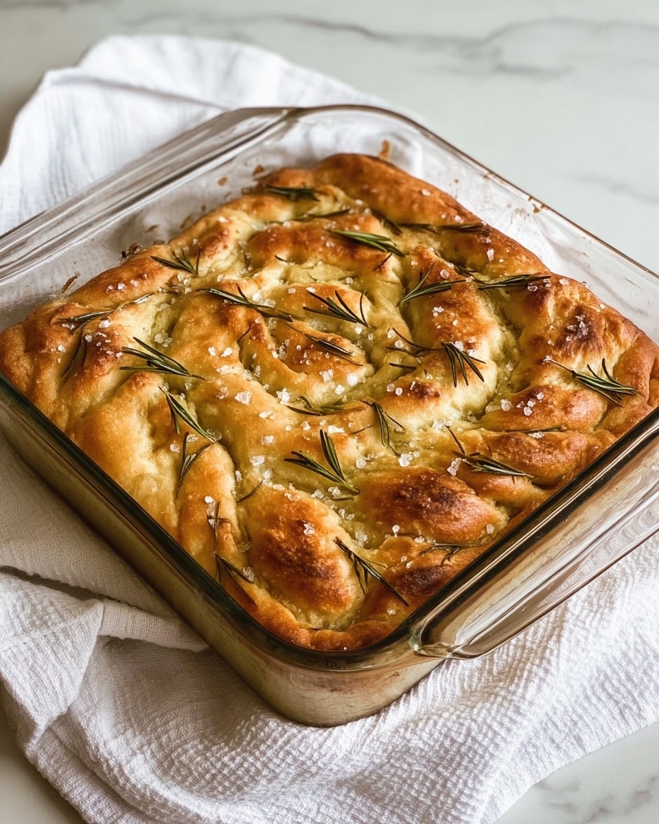 The image shows a thick, round focaccia bread with a golden brown top sprinkled with coarse salt and small green rosemary leaves. One large slice has been cut and laid in front of the main round piece, showing the airy, soft texture inside with visible small holes and some rosemary inside too. The crust looks crunchy and rough with browned parts where the dough bunched up in uneven rows. The focaccia is placed on a dark board, with a detailed close-up view capturing the different textures of the crust and soft inside. Photo taken with an iphone --ar 4:5 --v 7