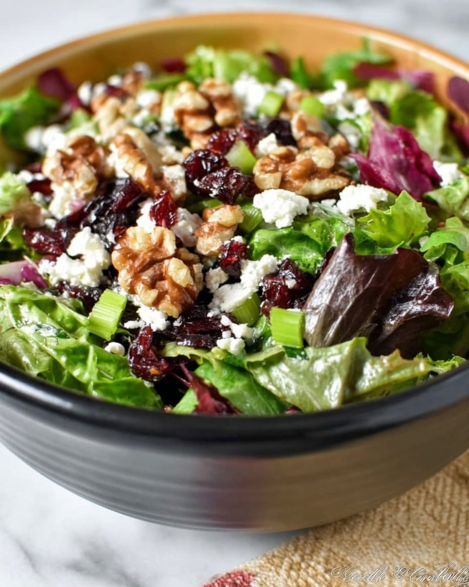 A close-up of a white bowl filled with a fresh layered salad. The bottom layer consists of mixed green and purple leafy lettuce, followed by scattered small green slices of celery. On top, there are generous clusters of chopped walnuts, crumbled white cheese, and small dark red dried cranberries spread evenly throughout. The textures vary from soft lettuce to crunchy nuts and chewy cranberries. The bowl is placed on a white marbled surface with a blurred background. Photo taken with an iphone --ar 4:5 --v 7