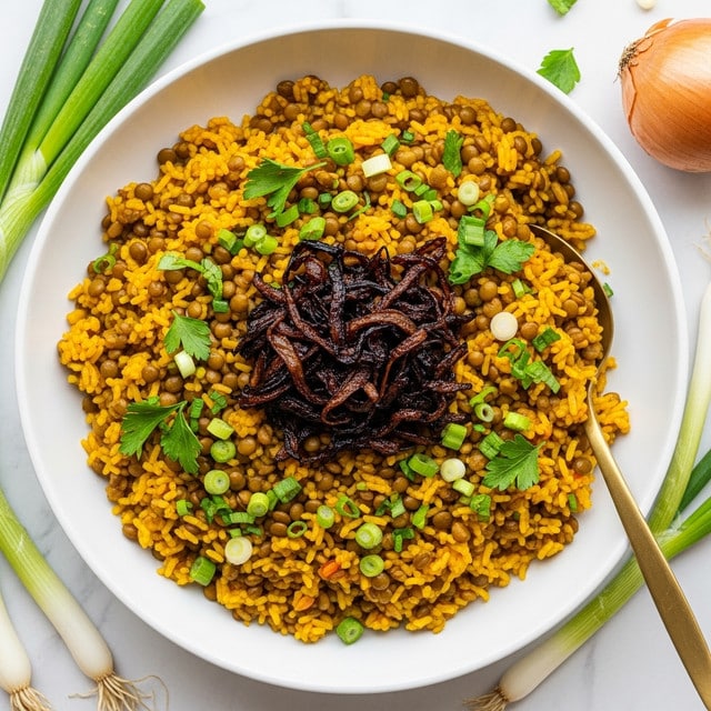 A large white bowl holds a vibrant dish with a base layer of yellow-orange cooked lentils and rice mixed together, creating a textured surface of small grains. On top, there is a central strip of glossy caramelized onions in a dark brown color, slightly sticky in appearance. Scattered across the dish are slices of fresh green scallions and bits of chopped green herbs, adding fresh pops of color to the warm tones. A shiny gold spoon is inserted on the right side of the bowl, partly resting in the rice mixture. The bowl is placed on a white marbled surface with hints of green onions and a blue cloth nearby, enhancing the colorful and appetizing look. Photo taken with an iphone --ar 4:5 --v 7