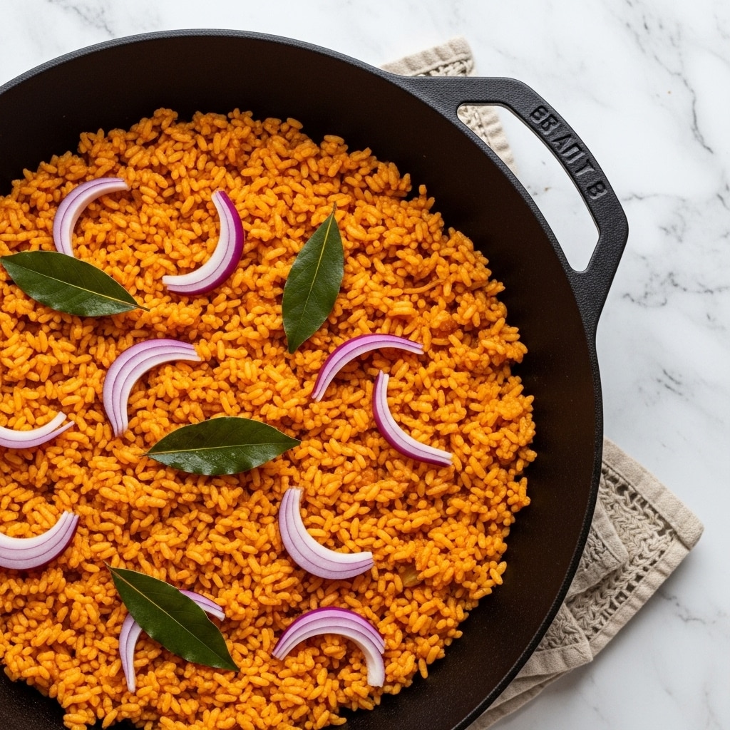 A black round pot filled with one layer of bright orange rice with a fluffy texture. The rice is decorated with thin, curved slices of light purple onions scattered on top alongside a few small green bay leaves. The pot is placed on a white marbled surface next to a textured beige cloth and a book with a brown and black cover. Photo taken with an iphone --ar 4:5 --v 7