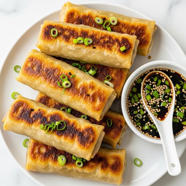 The image shows six golden-brown spring rolls arranged closely on a white plate with a white marbled background. Each roll has a slightly crispy and shiny outer layer, with grilled spots and small green onion pieces visible inside and on top. A small white spoon rests in a white bowl filled with dark soy dipping sauce sprinkled with sesame seeds and chopped green onions, placed at the edge of the plate. The spring rolls look freshly cooked with a mix of textures from crispy to soft. photo taken with an iphone --ar 4:5 --v 7