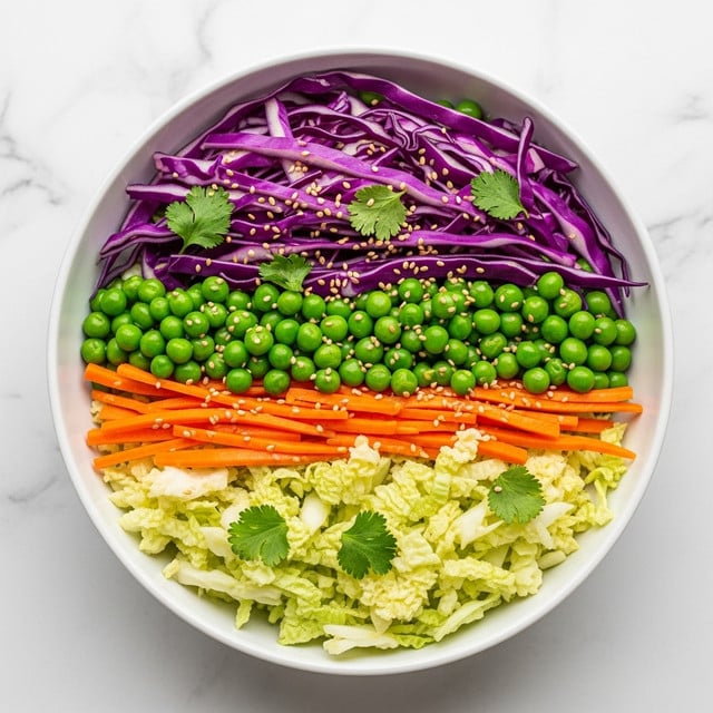 A white bowl filled with a colorful cabbage salad sits on a white marbled surface. The salad has three layers: the bottom layer is light green cabbage pieces with a soft texture, mixed evenly with thin orange carrot sticks; the middle layer has bright green peas scattered throughout; the top layer shows rich purple cabbage strips, with a few sprigs of fresh green cilantro and light sprinklings of sesame seeds adding texture and color contrast. photo taken with an iphone --ar 4:5 --v 7