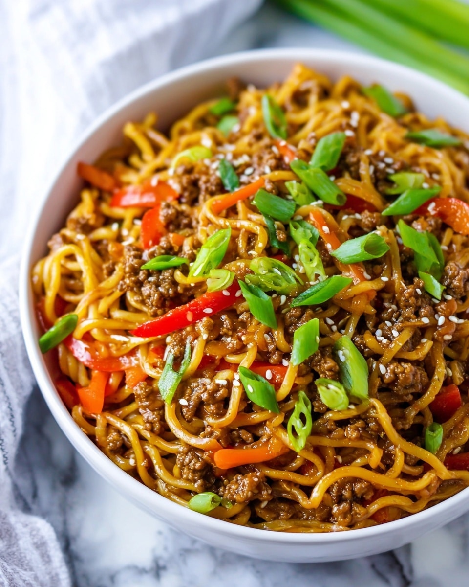 A white bowl filled with cooked noodles mixed with small pieces of browned ground meat, red bell pepper slices, and thin orange carrot strips, all coated in a glossy sauce. The dish is topped with chopped bright green scallions and sprinkled with small white sesame seeds. The bowl is placed on a white marbled surface, with some green scallion stalks visible in the background. photo taken with an iphone --ar 4:5 --v 7