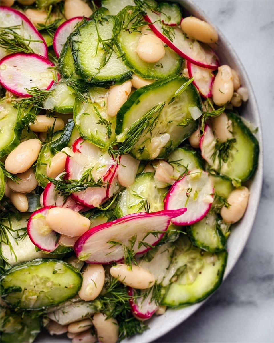 The image shows a white bowl filled with a fresh salad made of white beans, thinly sliced green cucumber rounds, and small pieces of red onion. The salad has a mix of creamy white and light green colors with hints of purple from the onion. A woman's hand holds a gold spoon inside the bowl, ready to serve the salad. The bowl is set on a white marbled surface, giving a clean and bright look. photo taken with an iphone --ar 4:5 --v 7