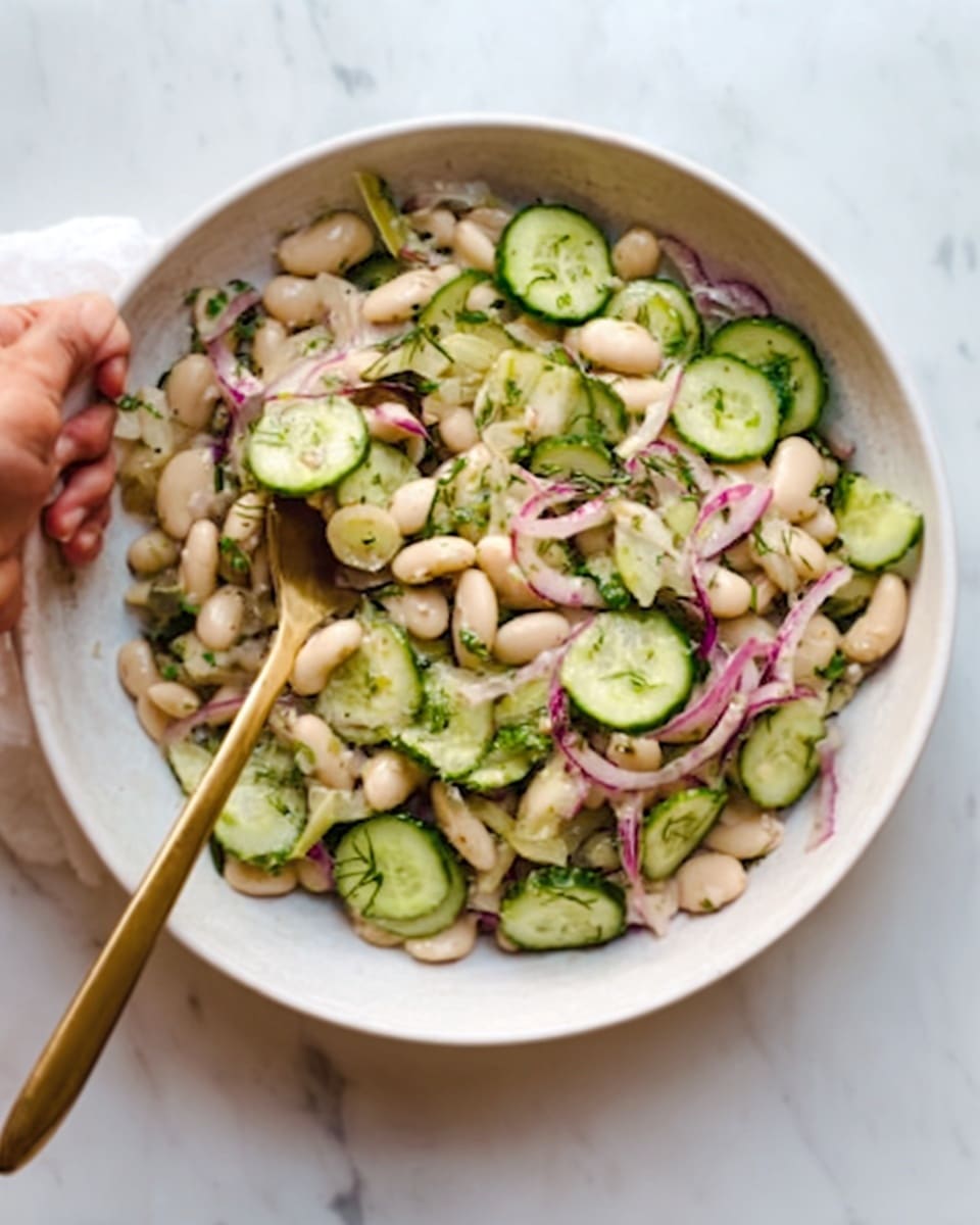 The image shows a close-up of a fresh salad in a white bowl, placed on a white marbled surface. The salad has several layers of ingredients: a base of white beans that look soft and creamy, mixed with thin slices of light green cucumber with dark edges, and thin strips of pale pink radish with red borders. Scattered throughout are small green dill leaves adding a soft feathery texture. The colors are fresh and natural, making the dish look healthy and crisp. Photo taken with an iphone --ar 4:5 --v 7