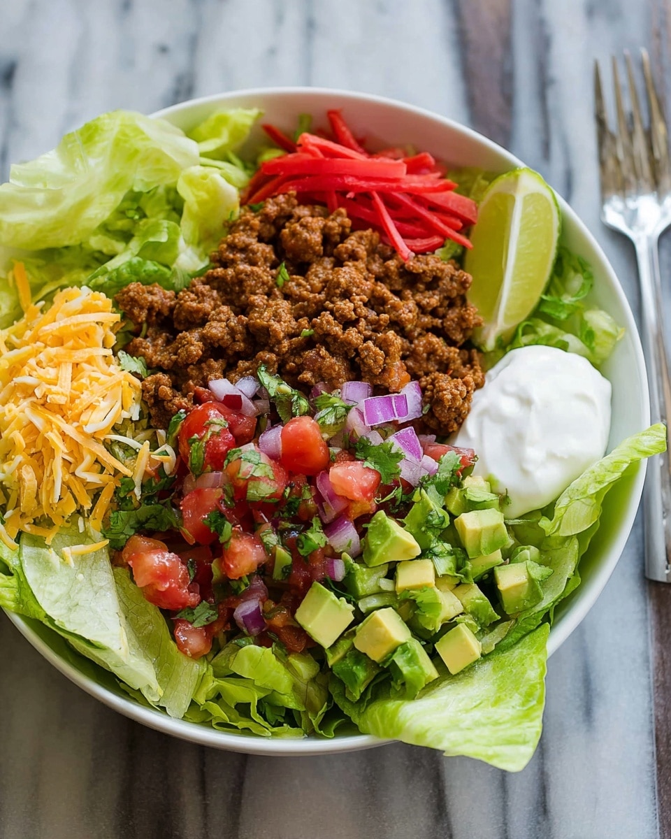 A white bowl-shaped tortilla with a slightly crispy, golden-brown edge forms the base of this dish. Inside, the first layer is finely shredded green lettuce spread evenly, topped by a layer of dark brown cooked ground beef. On top of the beef are fresh red tomato wedges and small chopped pieces of white and purple onion. Green avocado chunks and pale yellow shredded cheese are spread across the top. Dollops of white sour cream sauce and fresh green cilantro leaves finish the dish, adding contrast in color and texture. The bowl sits on a simple white plate against a white marbled surface. Photo taken with an iphone --ar 4:5 --v 7