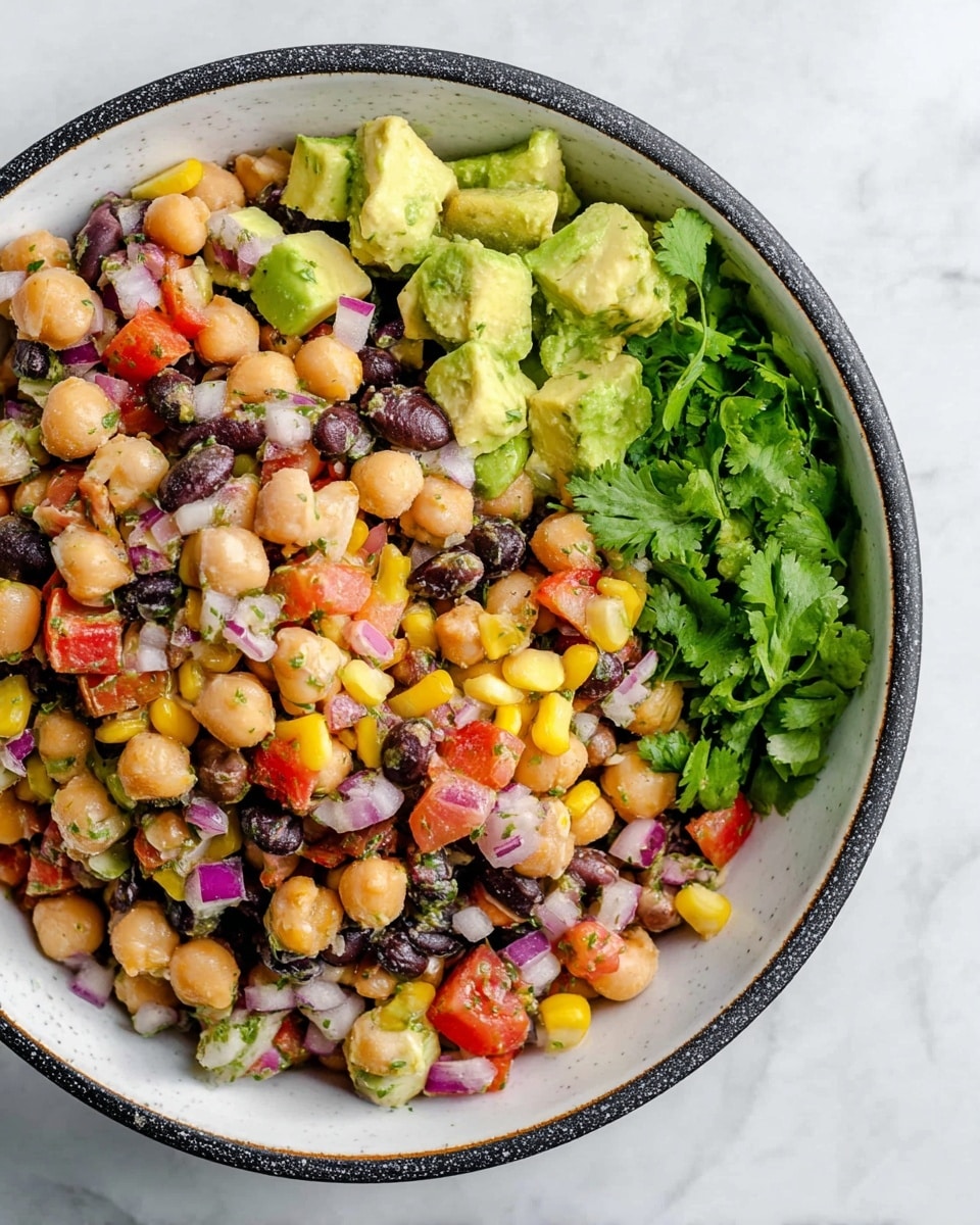 A white bowl with a dark rim holds a colorful mixed bean salad with several layers visible: the base layer is made of chickpeas, black beans, and pinto beans in soft beige, black, and light brown colors. Scattered throughout are bright yellow corn kernels and diced avocado pieces with a soft green and creamy texture. Small cubes of red onion add purple and white tones, while chopped red tomatoes bring pops of vibrant red. The salad is topped with fresh green cilantro leaves placed on one side, adding a leafy texture on top. The bowl rests on a white marbled background. Photo taken with an iphone --ar 4:5 --v 7