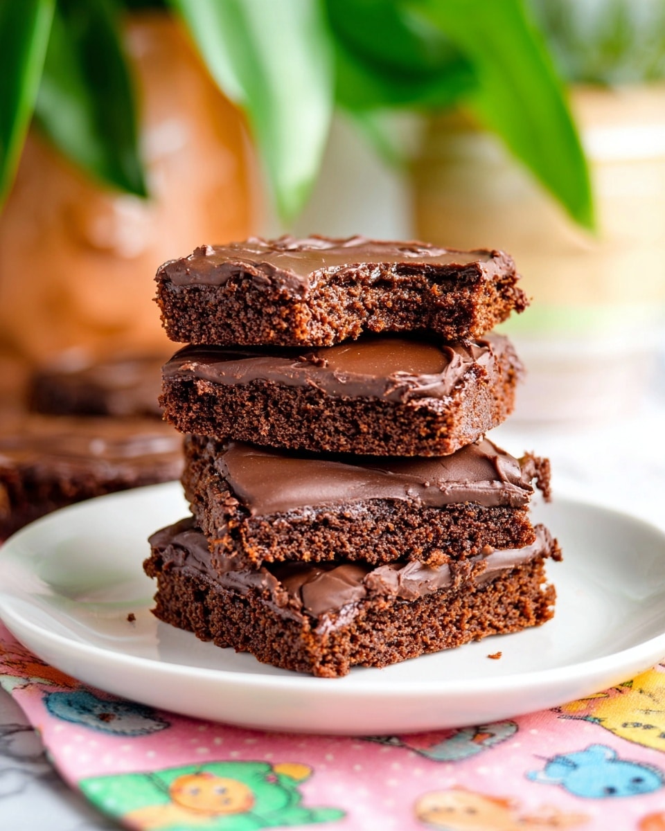 A stack of four square chocolate brownies is placed on a white plate resting on a colorful cloth with cartoon animal faces. Each brownie has two layers: a thick, dark brown cake base with a slightly crumbly texture, and a glossy, smooth chocolate frosting spread evenly on top. The top brownie is broken in half, showing the moist inside and rich chocolate layer. The background is softly blurred with green plant leaves and a container that add a fresh look, all set on a white marbled surface. Photo taken with an iphone --ar 4:5 --v 7