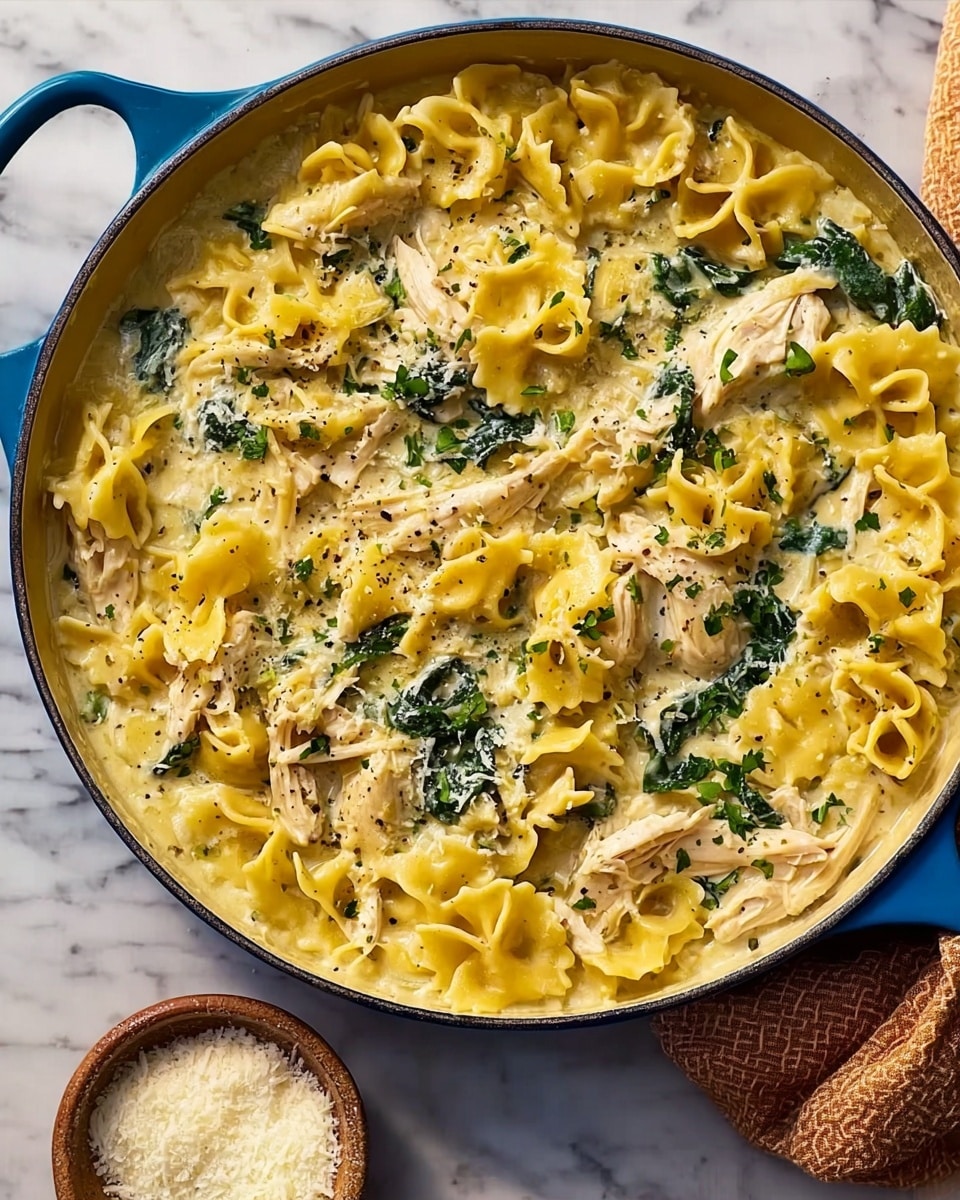 A close-up view of a bowl filled with creamy chicken noodle soup placed on a white marbled surface, the soup has a creamy, pale yellow broth with visible small pasta shapes in light yellow, tender shredded chicken pieces in off-white, and dark green spinach leaves scattered throughout; bits of herbs and red pepper flakes add speckles of green and red on top, creating a textured look. In the background, another bowl of the same soup is partially visible, slightly blurred, and there is a small white bowl with a finely grated white topping. The bowls are all white with a smooth texture. photo taken with an iphone --ar 4:5 --v 7