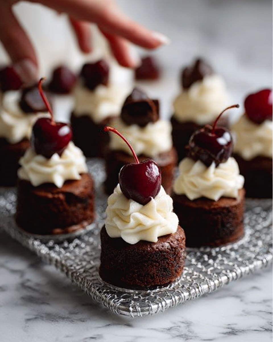 The image shows small round chocolate cakes with three visible layers: a dark chocolate base, a lighter chocolate middle, and a thick swirl of white cream on top. Each cake is topped with a shiny dark red cherry that has a thin stem. The cakes are placed on a dark metal grid resting on a white marbled surface, and a woman's hand is slightly touching one of the cakes. The overall look is rich and elegant with a focus on the contrast between dark chocolate, bright white cream, and deep red cherries. Photo taken with an iphone --ar 4:5 --v 7