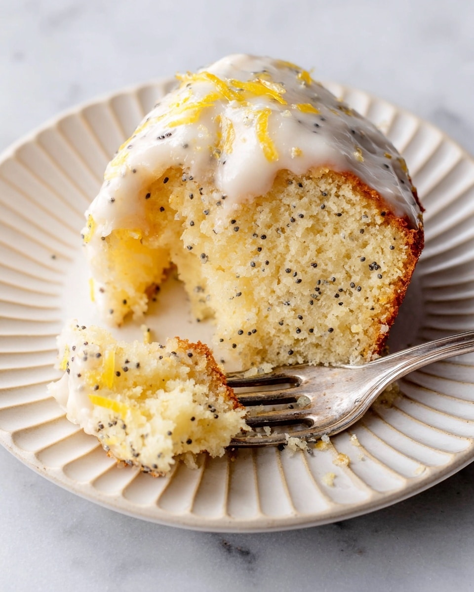 A close-up of a piece of soft lemon poppy seed cake on a white plate with ridges. The cake has a light yellow color with small black poppy seeds evenly spread throughout the spongy texture. On top, there is a smooth, creamy white icing layer with yellow zest bits and poppy seeds scattered over it. A bite has been taken out from the slice, and the piece is resting on a silver fork under the cake, showing the moist inside. The plate is set on a white marbled surface. photo taken with an iphone --ar 4:5 --v 7