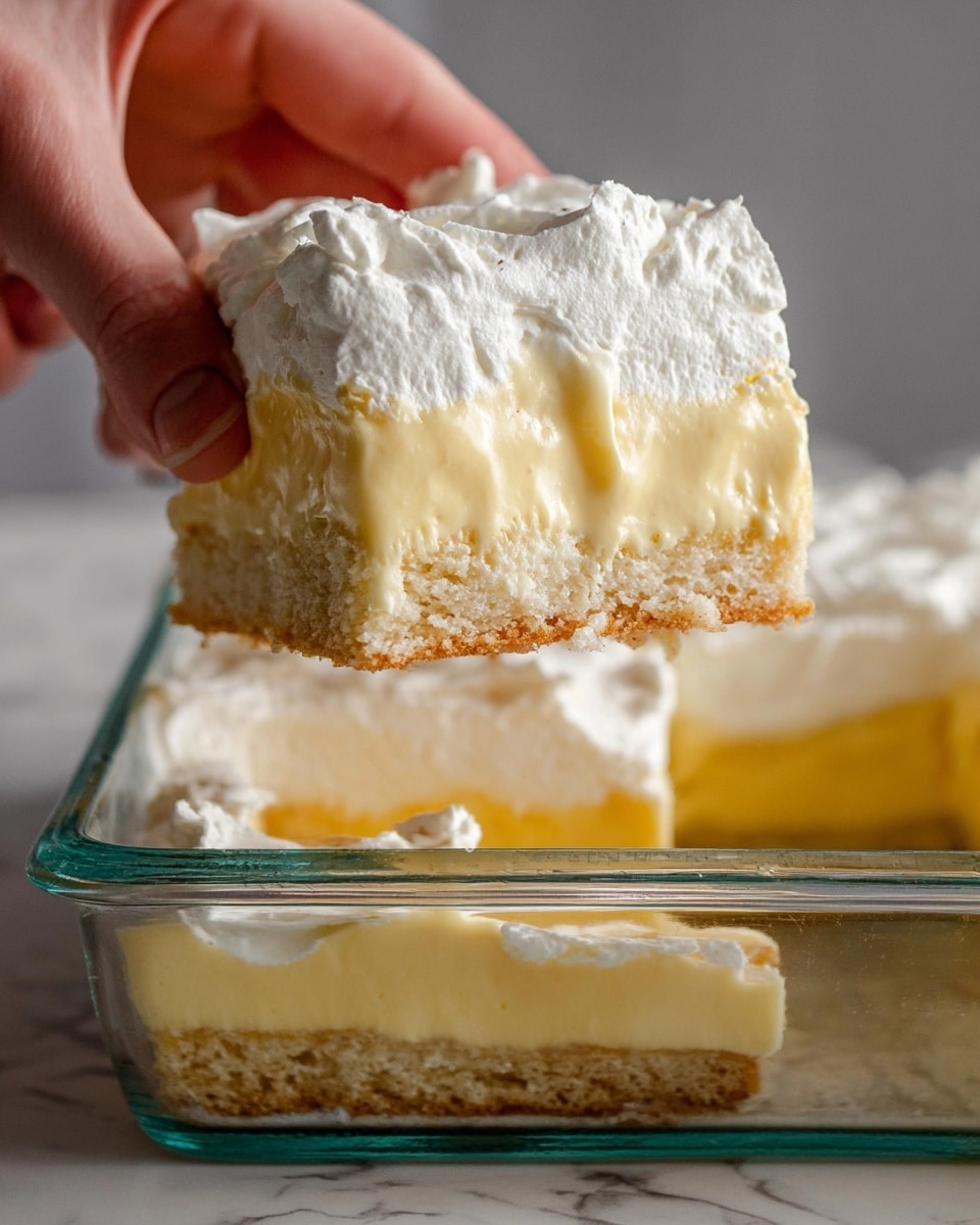 The image shows a slice of a three-layer dessert on a white plate. The bottom layer is a light tan, crispy, and textured base. The middle layer is a smooth, creamy, pale yellow custard. The top layer is a thick, fluffy white whipped topping with gentle ridges on the surface. In the background, part of the glass baking dish with the remaining dessert is visible on a white marbled surface with a blue and white cloth underneath. photo taken with an iphone --ar 4:5 --v 7