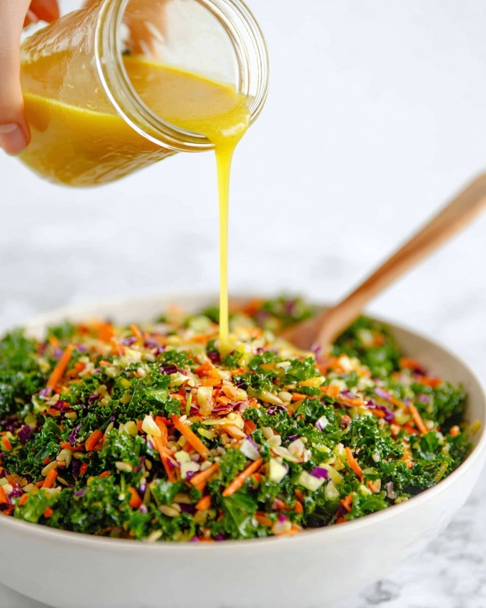 A close-up image shows a woman's hand pouring golden yellow dressing from a small clear glass jar over a large white bowl filled with a colorful mixed salad. The salad has multiple layers of finely chopped vegetables including bright green kale, orange carrot bits, purple cabbage, and small beige seeds, creating a rich textured and colorful mixture. A light wooden spoon rests inside the bowl on the bottom right side. The background surface is a white marbled texture, giving a clean and fresh look. photo taken with an iphone --ar 4:5 --v 7